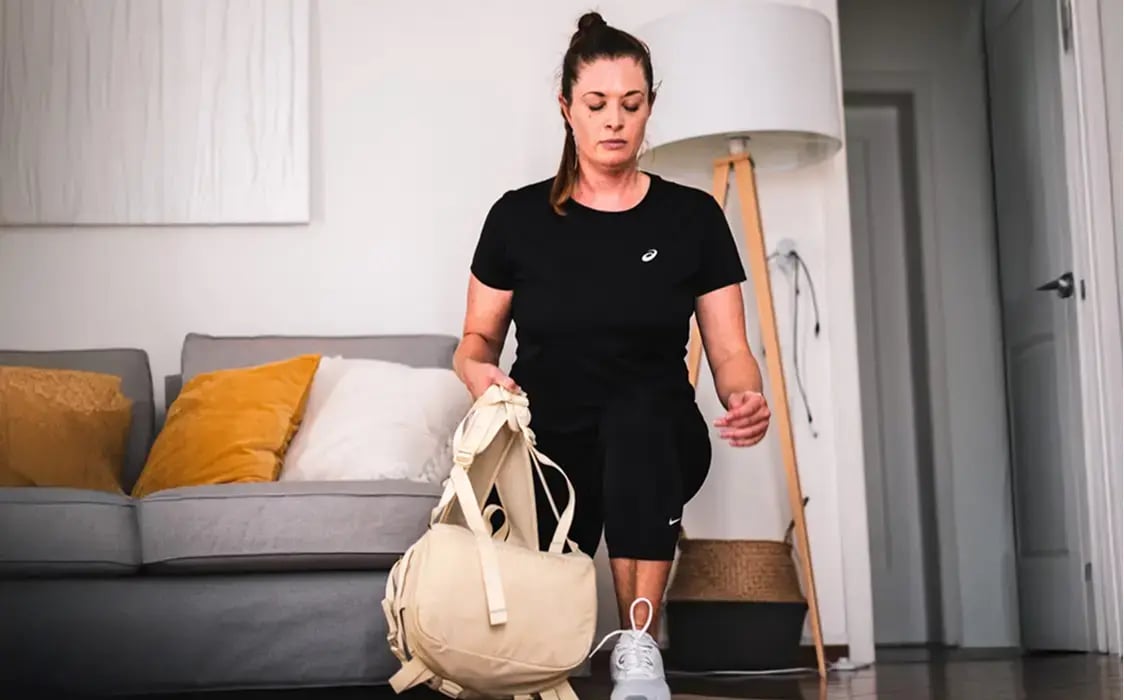 Frau trainiert Zuhause mit Rucksack als Gewicht