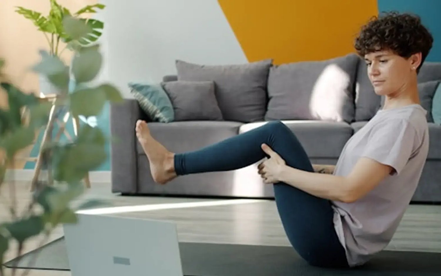 Frau trainiert Zuhause vor Laptop